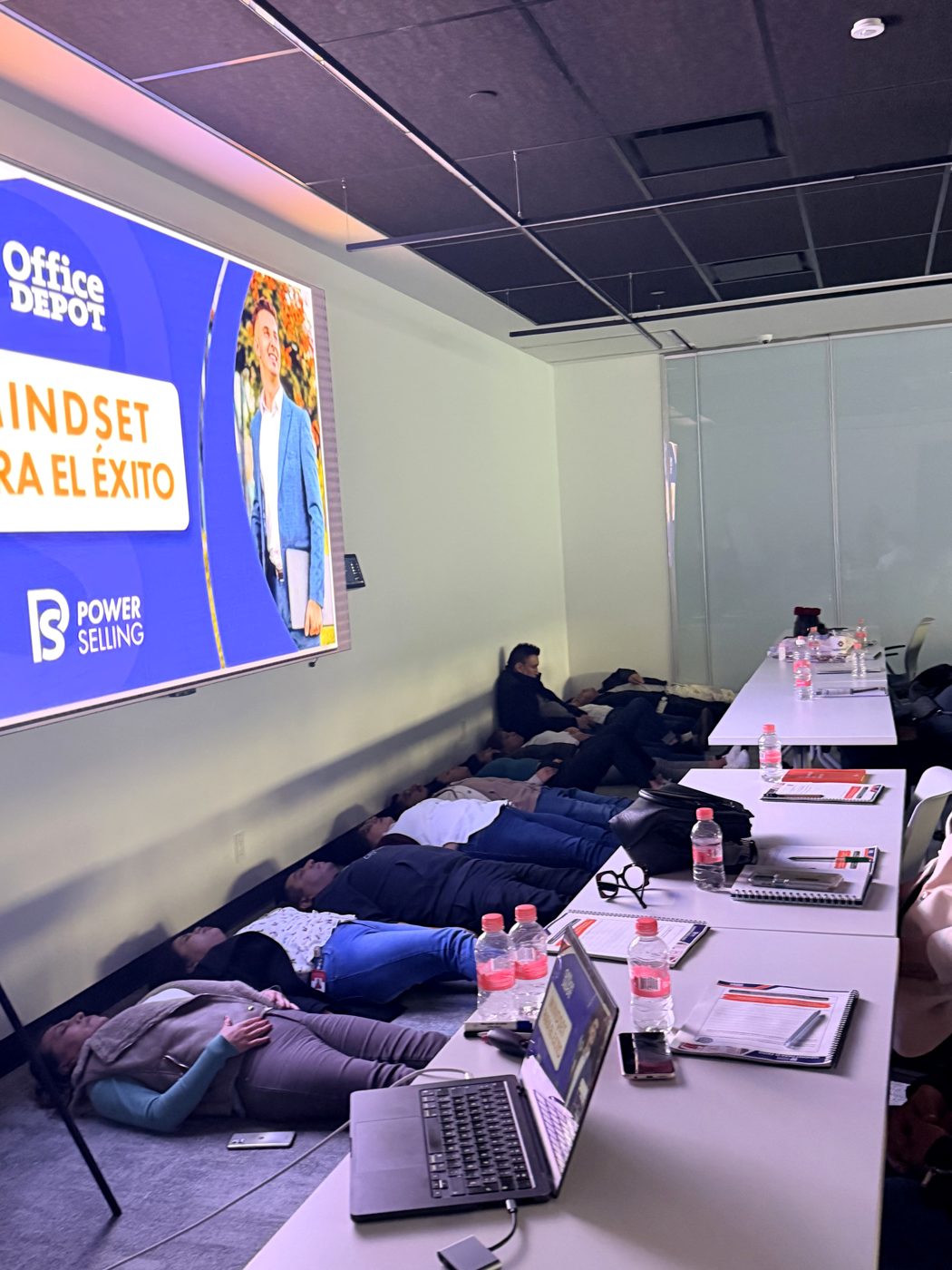 Participantes tumbados en el suelo durante un ejercicio de regulación, bajo la pantalla Mindset para el éxito